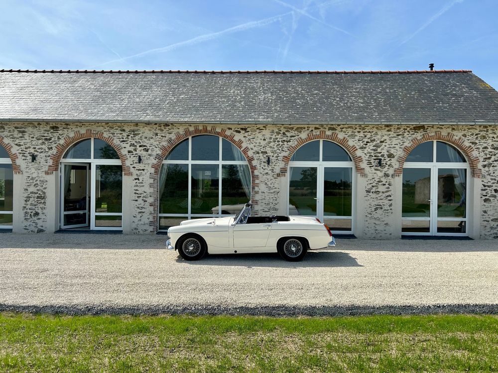 Façade en pierre du gîte, grandes arches vitrées